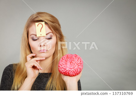 Woman thinking and holding fake brain 137310769