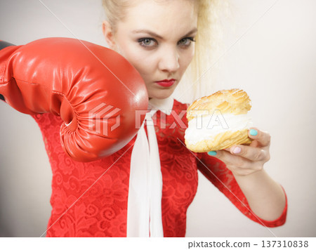 Woman fighting off bad food, boxing cream puff cake Woman fighting off bad food, boxing cream puff cake 137310838