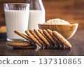 Oat cookies and milk are placed on a wooden table with a jar in the background for a simple snack time at home 137310865