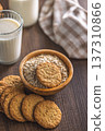 Cookies and oats are served in a bowl alongside a glass of milk on a wooden table at breakfast time 137310866