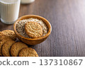 Cookies and oats are served in a bowl alongside a glass of milk on a wooden table at breakfast time 137310867