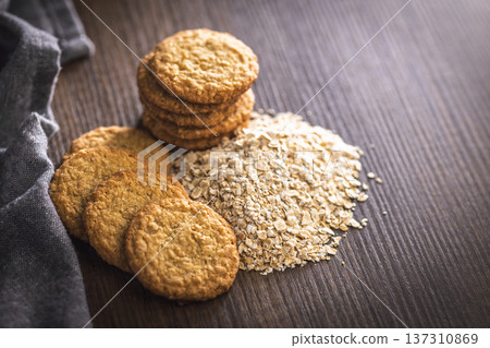 Cookies made with oats and oats scattered on wooden surface during daytime in a kitchen setting 137310869