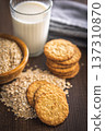 Cookies made with oats and oats scattered on wooden surface during daytime in a kitchen setting 137310870