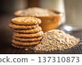 Cookies made with oats and oats scattered on wooden surface during daytime in a kitchen setting 137310873