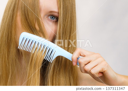 Woman combing long healthy blonde hair Woman combing long healthy blonde hair 137311347