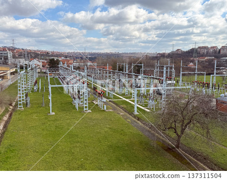 Electrical power substation infrastructure with transformer equipment cables and steel frames forming complex geometric industrial landscape. Energy distribution technology, electricity network 137311504