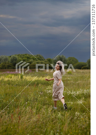 Woman Dressed In Light Linen Exploring Tranquil Field Filled With Wildflowers And Grass Woman Dressed In Light Linen Exploring Tranquil Field Filled With Wildflowers And Grass 137311716