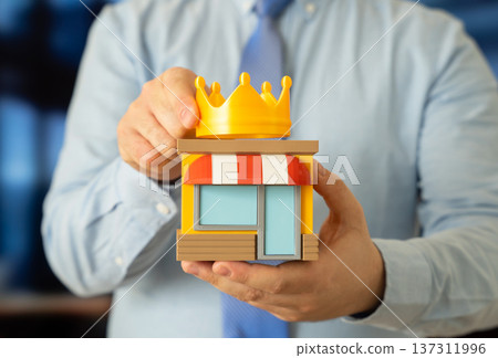 A man places a crown on a store. Best business first place award symbolizing retail leadership market dominance and entrepreneurial success. A man places a crown on a store. Best business first place award symbolizing retail leadership market dominance and entrepreneurial success. 137311996