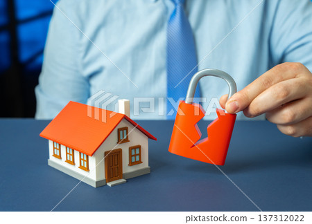 A residential building and a broken padlock. Security breach and vulnerability in protection systems exposing property to intrusion and safety risks. A residential building and a broken padlock. Security breach and vulnerability in protection systems exposing property to intrusion and safety risks. 137312022