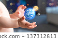 An infant's hands with dimpled knuckles stretch forward as a small globe appears above them, surrounded by floating planets in a playful background. 137312813