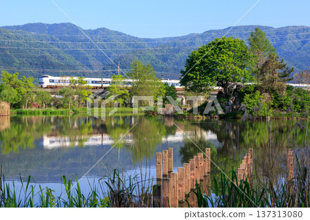 An express train runs through the calm early morning scenery of Lake Nukikawanaiko on the shores of Lake Biwa. An express train runs through the calm early morning scenery of Lake Nukikawanaiko on the shores of Lake Biwa. 137313080
