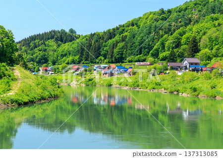 一列行駛在飯山線上的觀光列車經過千曲川沿岸的房屋。 137313085