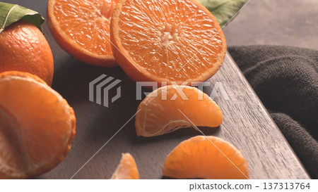 Freshly Cut Mandarin Oranges and Segments on a Dark Wood Board Freshly Cut Mandarin Oranges and Segments on a Dark Wood Board 137313764