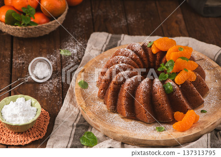 Glazed Orange Bundt Cake with Powdered Sugar and Fresh Mint on a Rustic Wooden Table 137313795