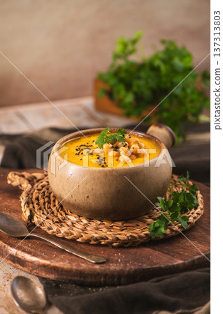 Creamy Pumpkin Soup with Chickpeas and Black Cumin in a Rustic Ceramic Bowl 137313803