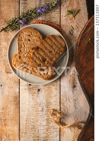 Toasted Sourdough Bread Slices on Plate with Rosemary and Rustic Wood Background Toasted Sourdough Bread Slices on Plate with Rosemary and Rustic Wood Background 137313807
