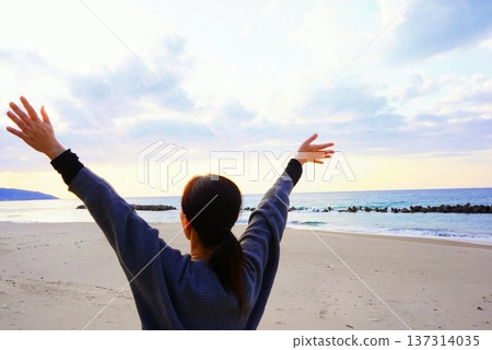 Back view of a woman taking a deep breath on the beach 137314035