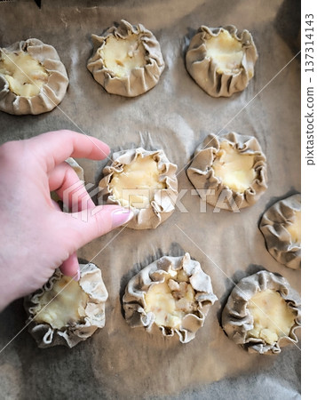 The process of making traditional Karelian kalitki from rye flour with potatoes on a baking sheet 137314143