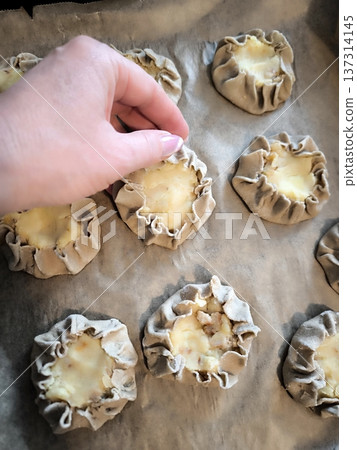 Cooking traditional Karelian kalitki made from rye flour and potatoes on a baking sheet. Cooking traditional Karelian kalitki made from rye flour and potatoes on a baking sheet. 137314145