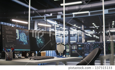 AI development workstation in data center with dual monitors displaying machine learning code. Server hub computers used for tracking neural network structures algorithm performance 137315133