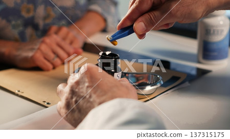 Senior specialist preparing all the pills and supplements for the woman patient, explaining the treatment and dosage for wellness. Medic expert prescribing the medicaments and drugs. Camera B. 137315175
