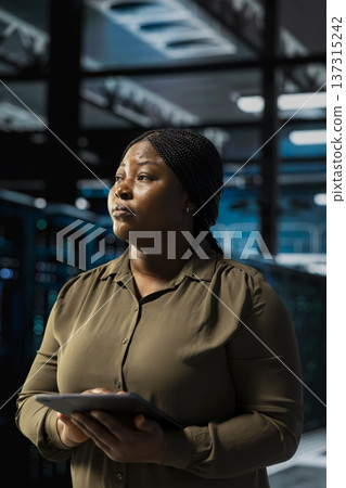Data center software developer installing and configuring hardware used for hosting digital services. African american server room worker testing and repairing rigs managing file transfers 137315242