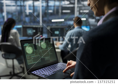 IT expert in server farm supporting international cloud services using notebook. Data center system administrator maintaining secure connectivity for global clients using laptop 137315251