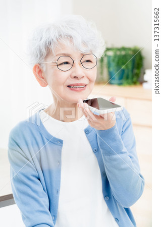 一位老年婦女正在對著智慧型手機說話 137315662