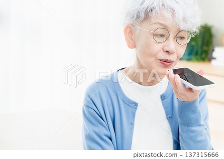 一位老年婦女正在對著智慧型手機說話 137315666