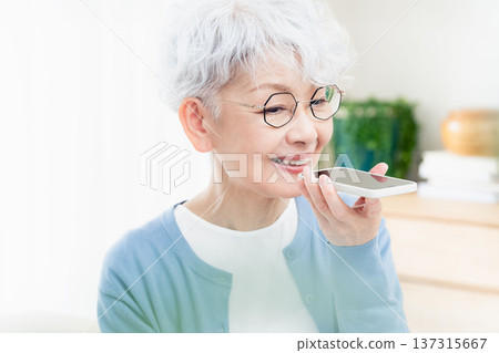 一位老年婦女正在對著智慧型手機說話 137315667