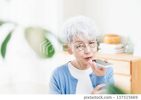 一位老年婦女正在對著智慧型手機說話 137315669