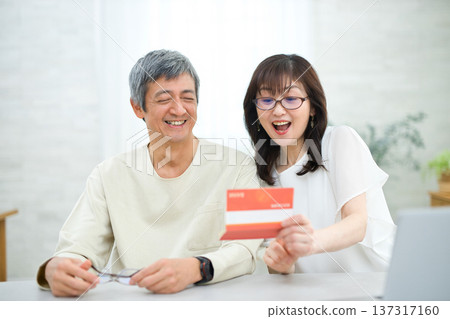 一對六十多歲的夫婦正在客廳裡查看他們的儲蓄存摺。 一對六十多歲的夫婦正在客廳裡查看他們的儲蓄存摺。 137317160