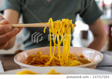 Someone try to eating Khao soi (Northern Thai Coconut Curry Noodle Soup). Khao soi is one of the most popular Thai dishes to eat in northern Thailand, especially in Chiang Mai and Chiang Rai. Someone try to eating Khao soi (Northern Thai Coconut Curry Noodle Soup). Khao soi is one of the most popular Thai dishes to eat in northern Thailand, especially in Chiang Mai and Chiang Rai. 137317203