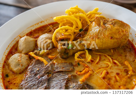 Close up of mixed Khao soi (Northern Thai Coconut Curry Noodle Soup). Khao soi is one of the most popular Thai dishes to eat in northern Thailand, especially in Chiang Mai and Chiang Rai. Close up of mixed Khao soi (Northern Thai Coconut Curry Noodle Soup). Khao soi is one of the most popular Thai dishes to eat in northern Thailand, especially in Chiang Mai and Chiang Rai. 137317206