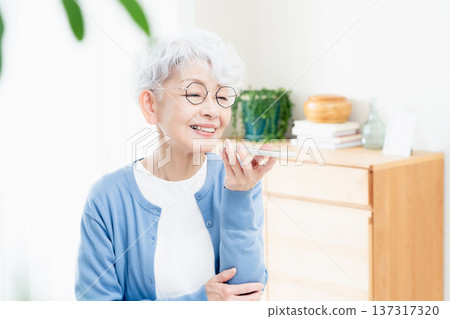 一位老年婦女正在對著智慧型手機說話 137317320