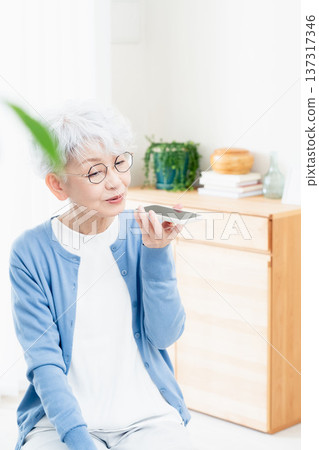 一位老年婦女正在對著智慧型手機說話 137317346