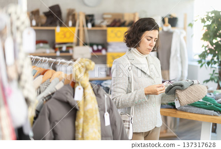 Latin American woman search and choose warm hat in shop 137317628