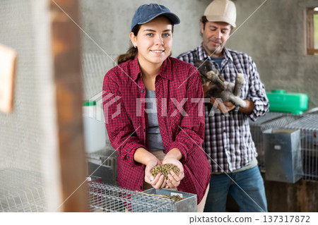 Married couple feeds and cares for rabbits on farm Married couple feeds and cares for rabbits on farm 137317872
