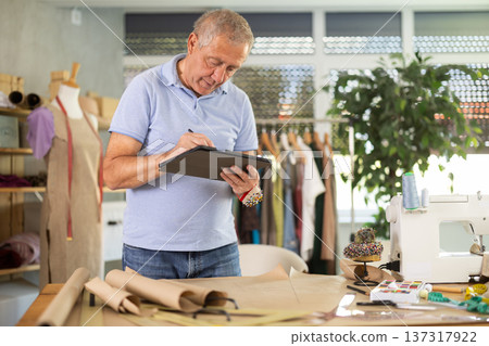 Man tailor makes pattern using tablet Man tailor makes pattern using tablet 137317922