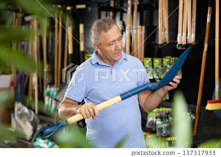 Man choosing shovel in store Man choosing shovel in store 137317933