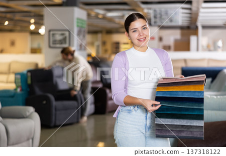 Female furniture salesperson showing different fabric samples in furniture showroom Female furniture salesperson showing different fabric samples in furniture showroom 137318122