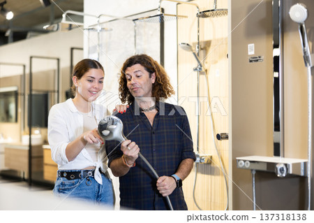 in plumbing department,man and woman examine shower head and quality of metal coating. in plumbing department,man and woman examine shower head and quality of metal coating. 137318138
