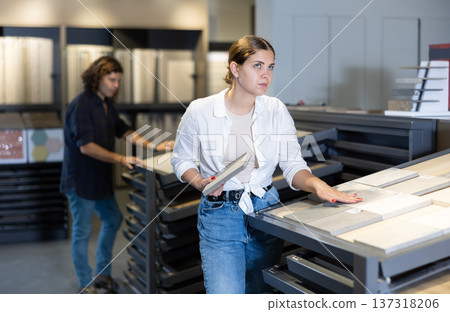 female buyer inspects small decorative tiles for redecorate apartment of new flat. Interior decor female buyer inspects small decorative tiles for redecorate apartment of new flat. Interior decor 137318206