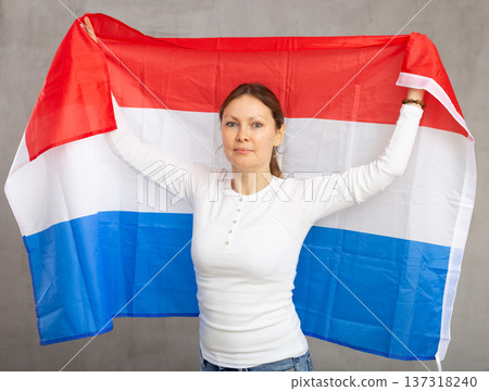 Attractive female football fan holding Netherlands flag 137318240