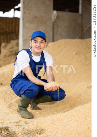 Positive male farmer with handful of soybean husk feed in hands 137318259