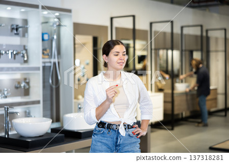 Portrait of female customer making a choice in plumbing and building materials store Portrait of female customer making a choice in plumbing and building materials store 137318281