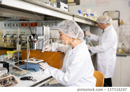 Skillful female scientist putting sample slide under microscope in lab Skillful female scientist putting sample slide under microscope in lab 137318297