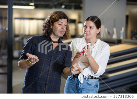 Hardware store employee showing client selection of materials on phone Hardware store employee showing client selection of materials on phone 137318306