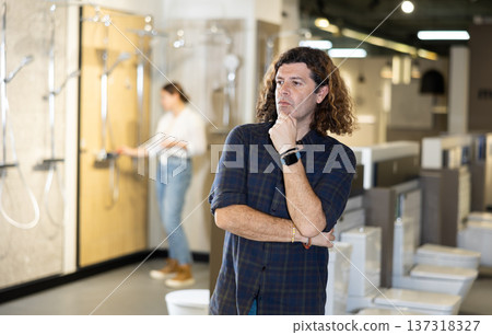Confident male customer looking around in bathroom section of hardware store Confident male customer looking around in bathroom section of hardware store 137318327