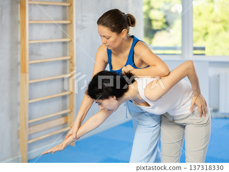 Woman is practicing self defence moves in pair with her female trainer at gym Woman is practicing self defence moves in pair with her female trainer at gym 137318330